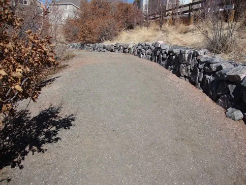 Wide crusher fine path running beside a dry-stacked stone retaining wall